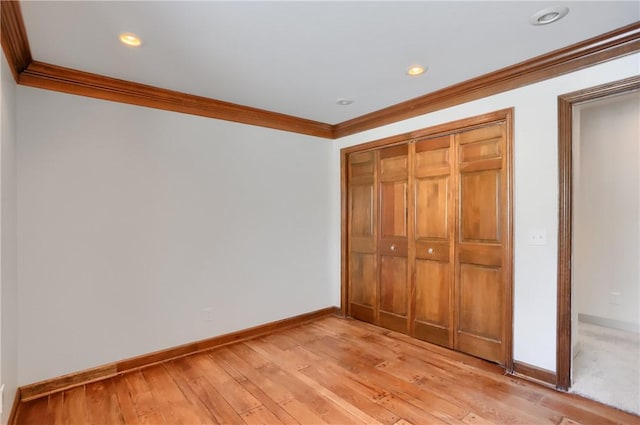 unfurnished bedroom with a closet, ornamental molding, and light hardwood / wood-style flooring