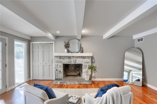 living room with a fireplace, beam ceiling, and hardwood / wood-style floors