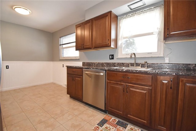 kitchen with light tile patterned floors, dishwasher, sink, and dark stone countertops