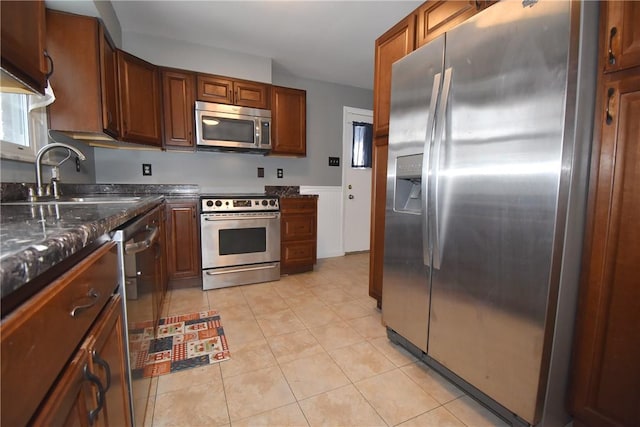 kitchen featuring light tile patterned floors, sink, appliances with stainless steel finishes, and dark stone countertops