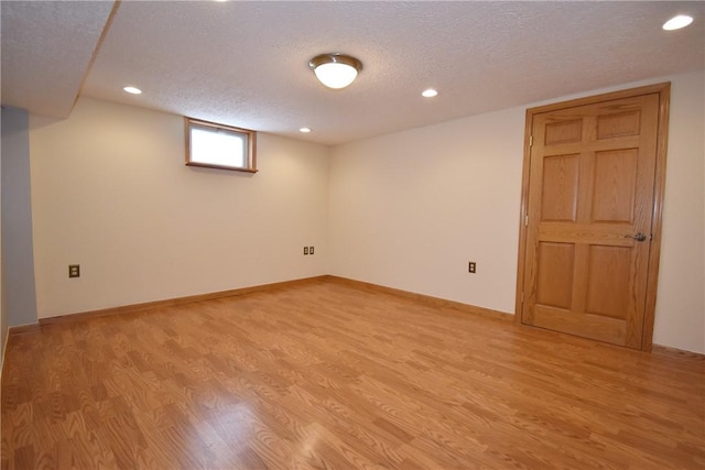 basement featuring light hardwood / wood-style floors and a textured ceiling