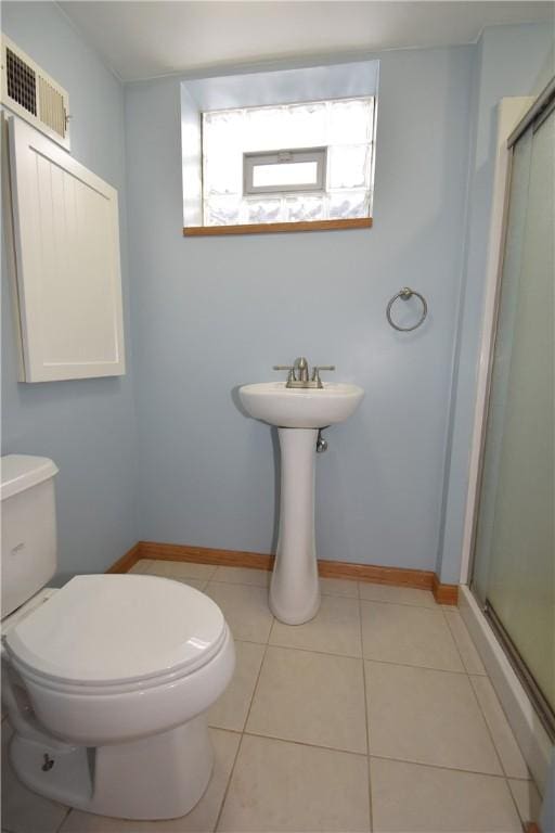 bathroom featuring an enclosed shower, tile patterned floors, and toilet