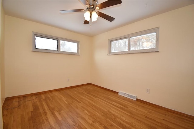 empty room with ceiling fan, a healthy amount of sunlight, and hardwood / wood-style floors