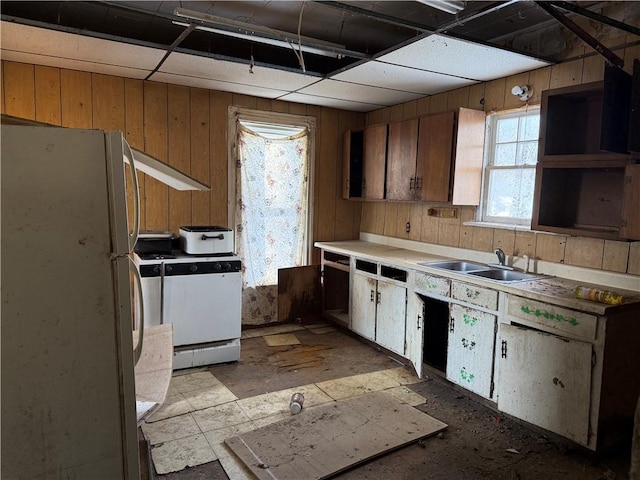 kitchen with sink, wood walls, and white fridge