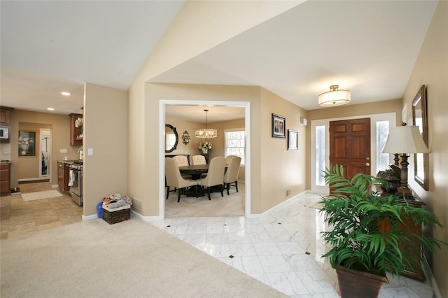 foyer entrance with light carpet and an inviting chandelier