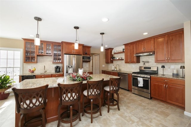 kitchen featuring stainless steel appliances, tasteful backsplash, a kitchen island, and decorative light fixtures