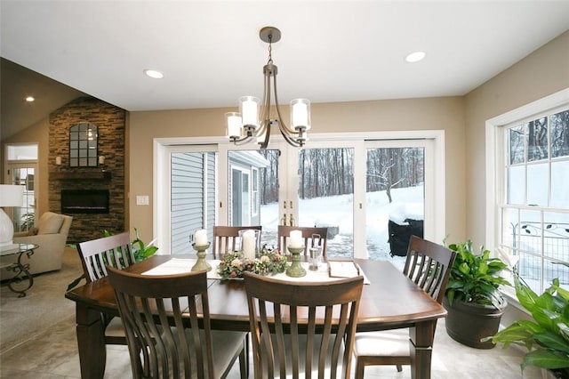 dining space featuring a stone fireplace and an inviting chandelier