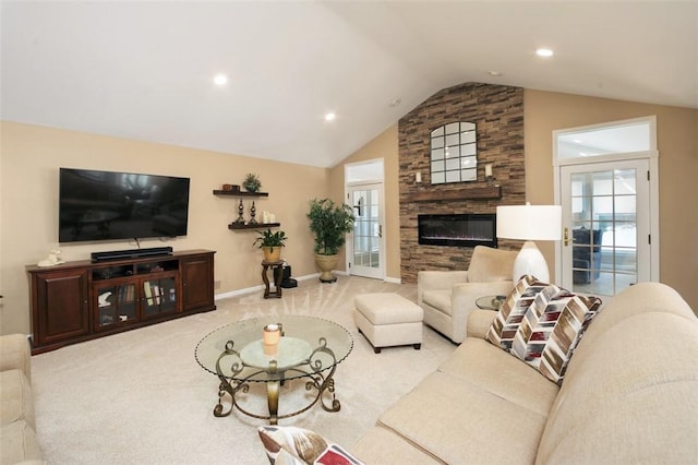 living room featuring a healthy amount of sunlight, a stone fireplace, vaulted ceiling, and light carpet