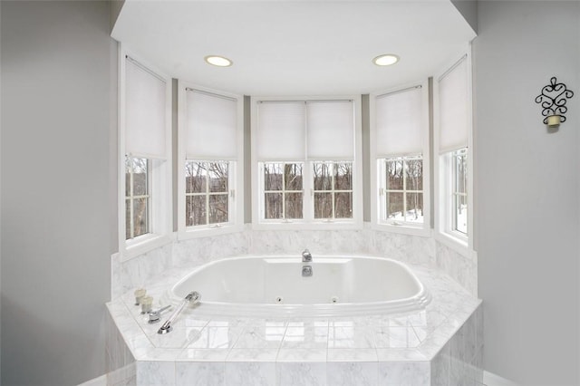 bathroom with a healthy amount of sunlight and tiled bath