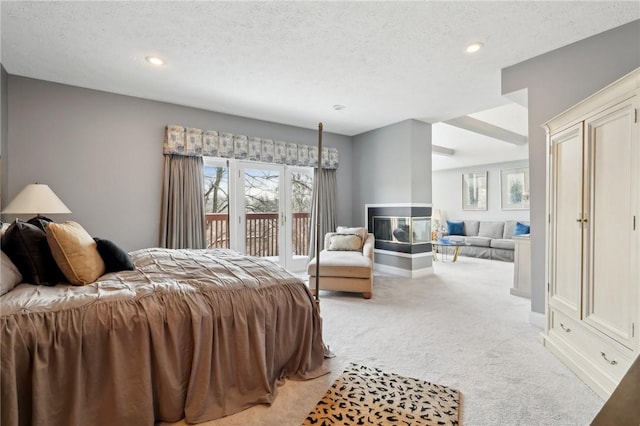 carpeted bedroom with access to outside, a multi sided fireplace, and a textured ceiling