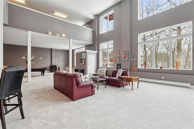 carpeted living room featuring a baseboard radiator, billiards, and a towering ceiling