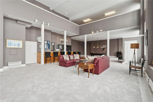 carpeted living room featuring a high ceiling and beamed ceiling