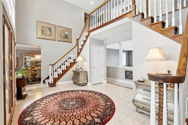 foyer entrance featuring decorative columns, plenty of natural light, light tile patterned floors, and a towering ceiling