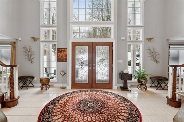 entryway featuring a high ceiling, french doors, and light tile patterned flooring