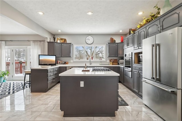 kitchen featuring a breakfast bar, a textured ceiling, appliances with stainless steel finishes, and a kitchen island