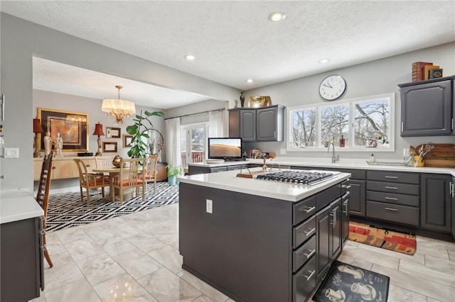 kitchen with a center island, sink, a textured ceiling, and pendant lighting