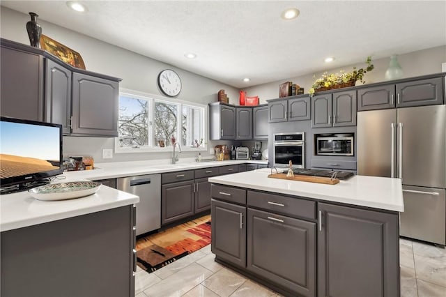 kitchen featuring a center island, sink, light tile patterned flooring, appliances with stainless steel finishes, and gray cabinetry