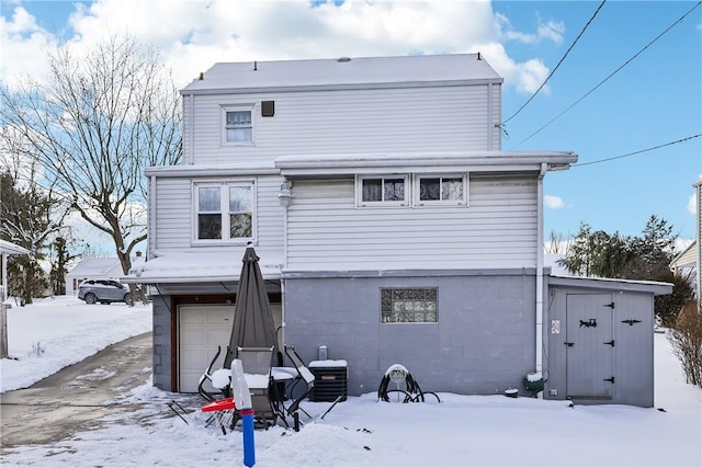 snow covered rear of property with a garage