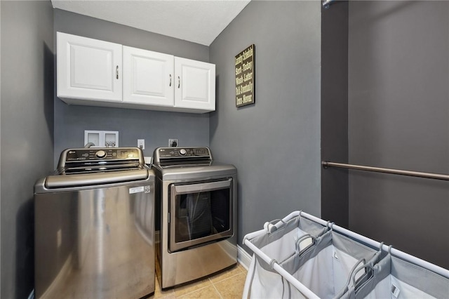 laundry room with light tile patterned floors, cabinets, and washing machine and clothes dryer