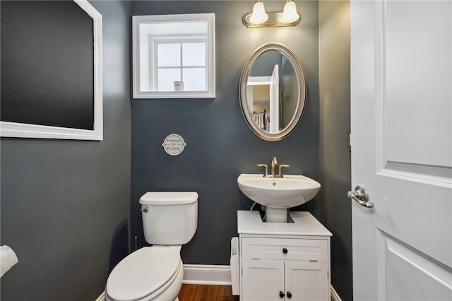 bathroom with toilet, sink, and hardwood / wood-style floors