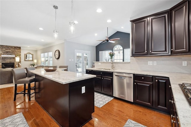 kitchen with sink, hanging light fixtures, a kitchen bar, a kitchen island, and stainless steel dishwasher