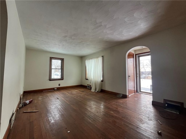 unfurnished room featuring a wealth of natural light and dark hardwood / wood-style flooring