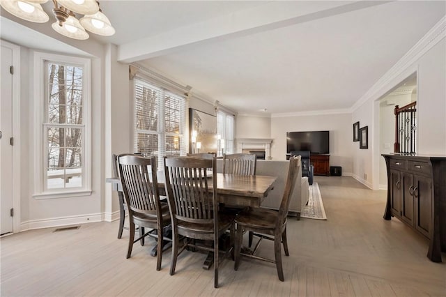 dining area featuring a notable chandelier, ornamental molding, and light hardwood / wood-style floors