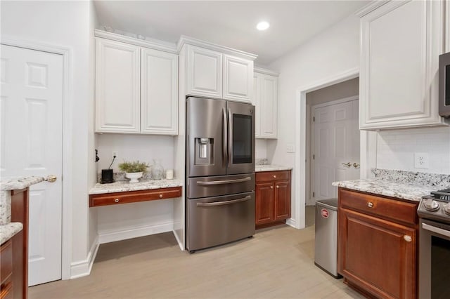 kitchen featuring appliances with stainless steel finishes, decorative backsplash, white cabinets, and light stone countertops