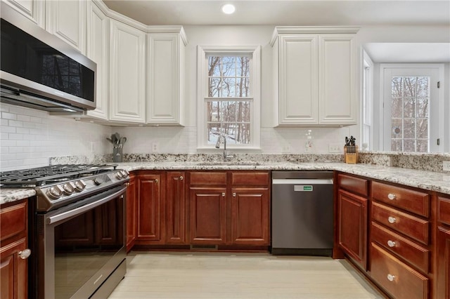 kitchen featuring decorative backsplash, sink, white cabinetry, stainless steel appliances, and light stone counters