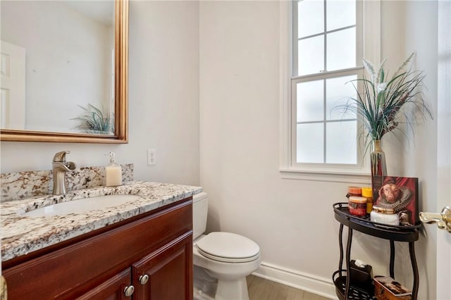 bathroom featuring toilet, vanity, and hardwood / wood-style floors