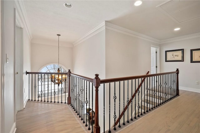 hall with light wood-type flooring, a chandelier, and ornamental molding