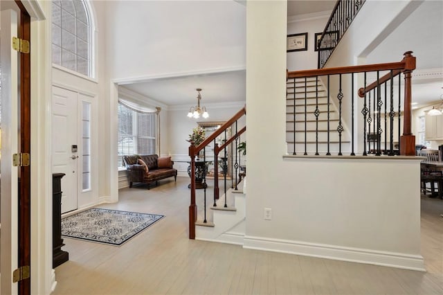 foyer with crown molding, a chandelier, and light hardwood / wood-style floors