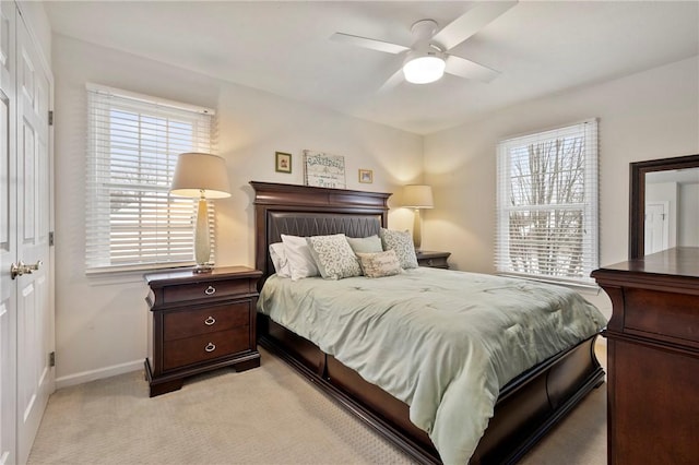 bedroom featuring ceiling fan, light colored carpet, and multiple windows