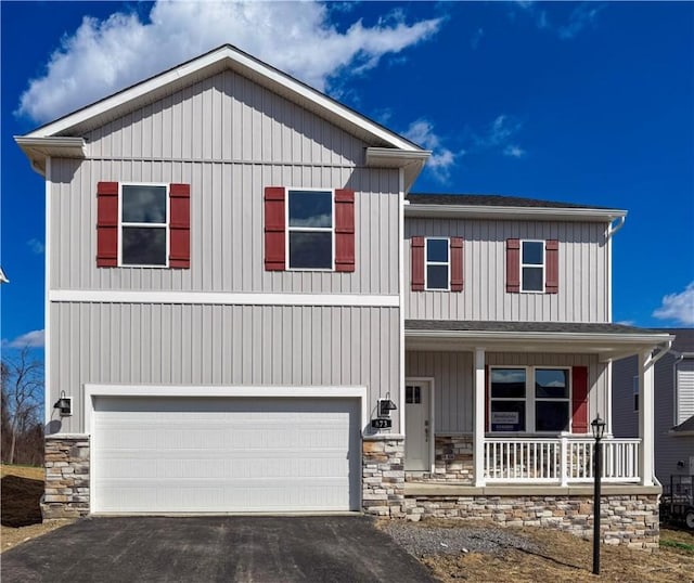 view of front of property with a garage, stone siding, covered porch, and driveway