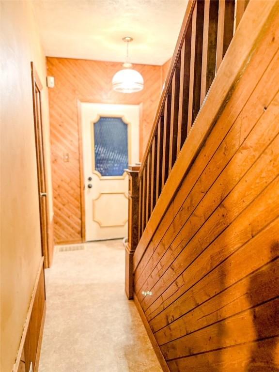 corridor featuring light carpet and wooden walls