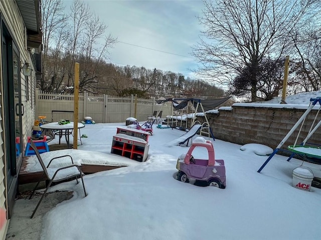 snow covered parking area with a playground and a trampoline