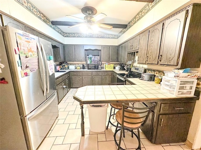 kitchen featuring light tile patterned floors, kitchen peninsula, stainless steel appliances, tile counters, and a kitchen breakfast bar