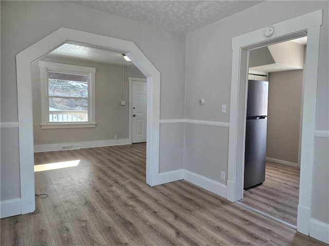 additional living space with a textured ceiling and light hardwood / wood-style flooring