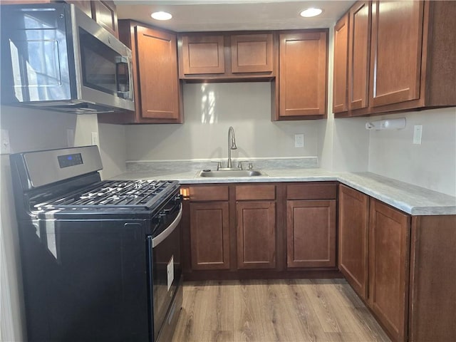 kitchen featuring range with gas cooktop, sink, and light hardwood / wood-style floors