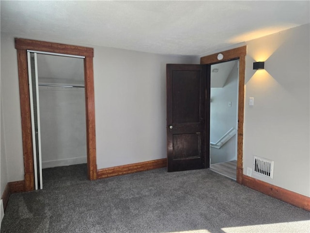 unfurnished bedroom with a closet and dark carpet