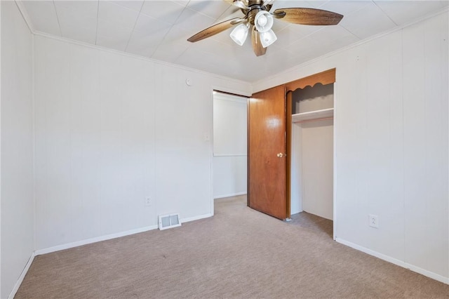 unfurnished bedroom featuring light carpet, ceiling fan, crown molding, and a closet