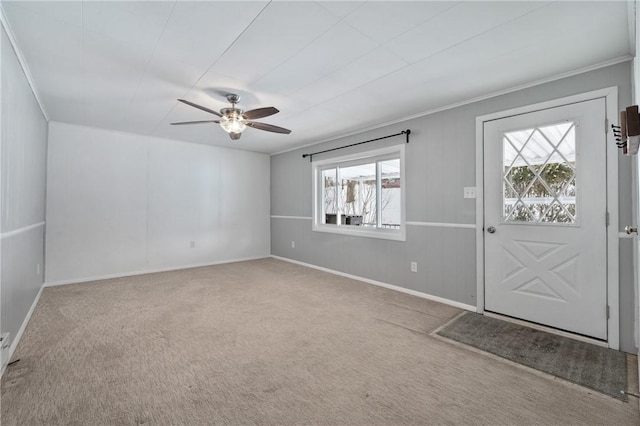 carpeted entrance foyer with ceiling fan and ornamental molding