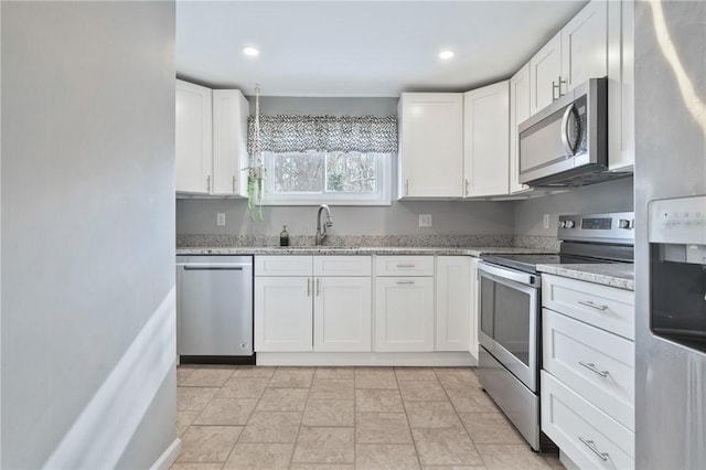 kitchen featuring light stone countertops, stainless steel appliances, white cabinets, and sink