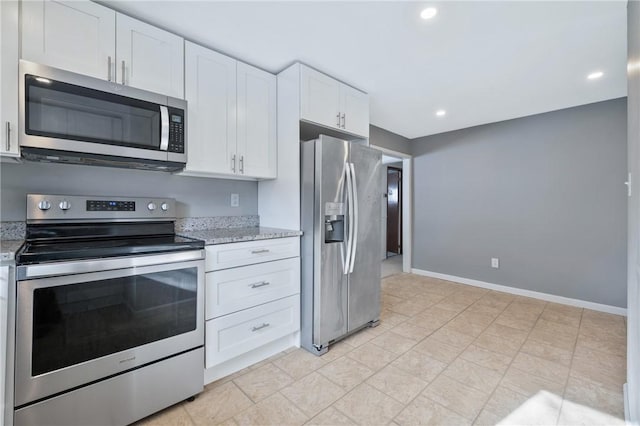 kitchen with stainless steel appliances, white cabinetry, and light stone countertops