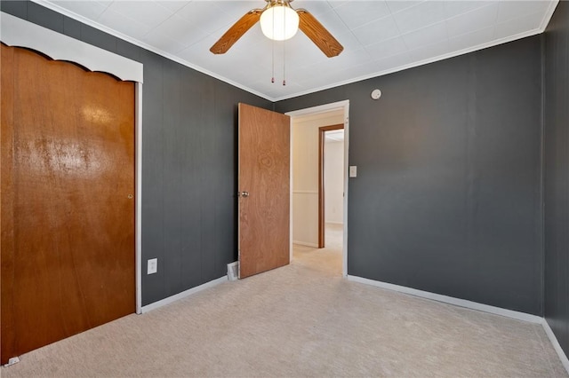 carpeted spare room featuring ceiling fan and crown molding