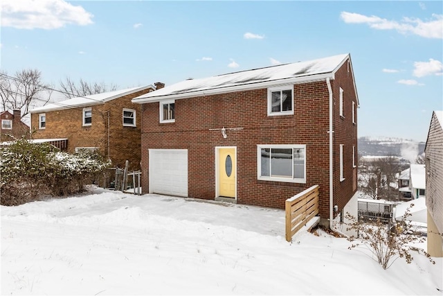 snow covered rear of property featuring a garage