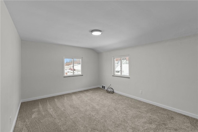 carpeted empty room with vaulted ceiling