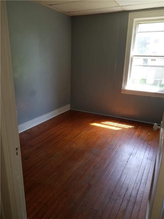 spare room with dark hardwood / wood-style floors and a paneled ceiling