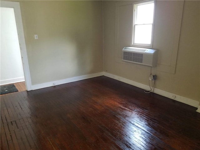 unfurnished room featuring a wall mounted air conditioner and dark hardwood / wood-style floors