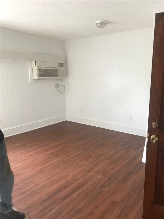 empty room featuring dark wood-type flooring and a wall unit AC